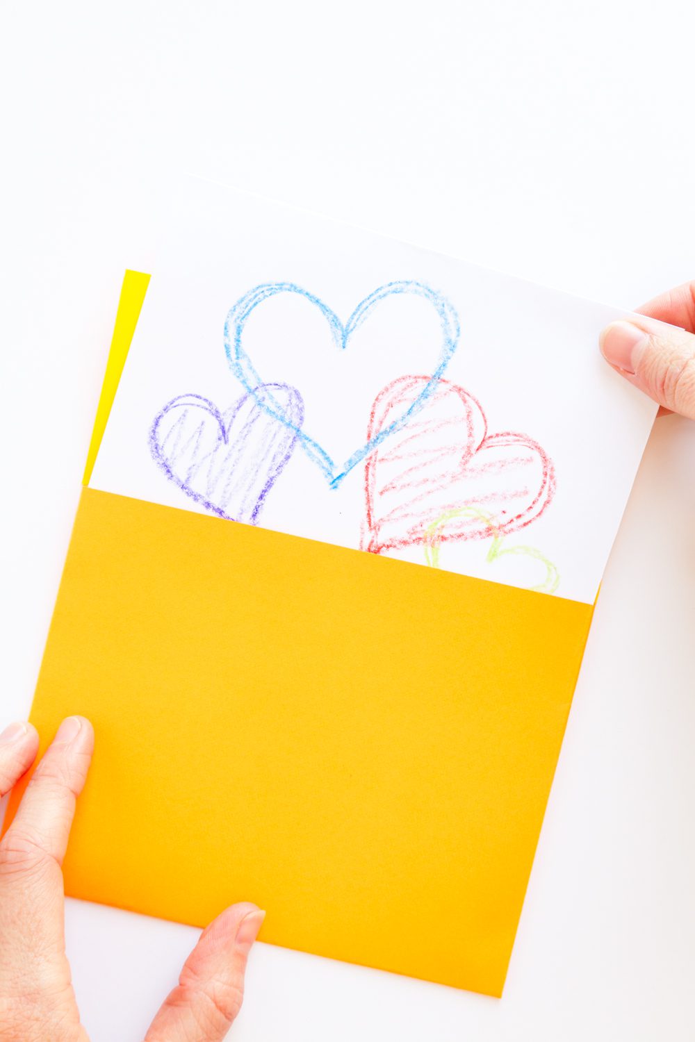 Pulling a card with colorful hearts from a yellow handmade square envelope.