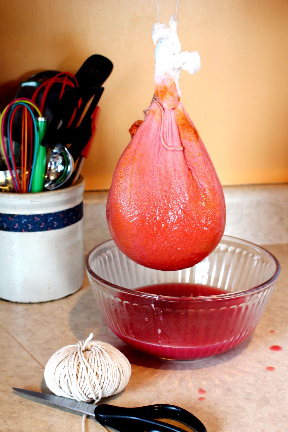 A cheesecloth straining fruit jelly liquid into a bowl.