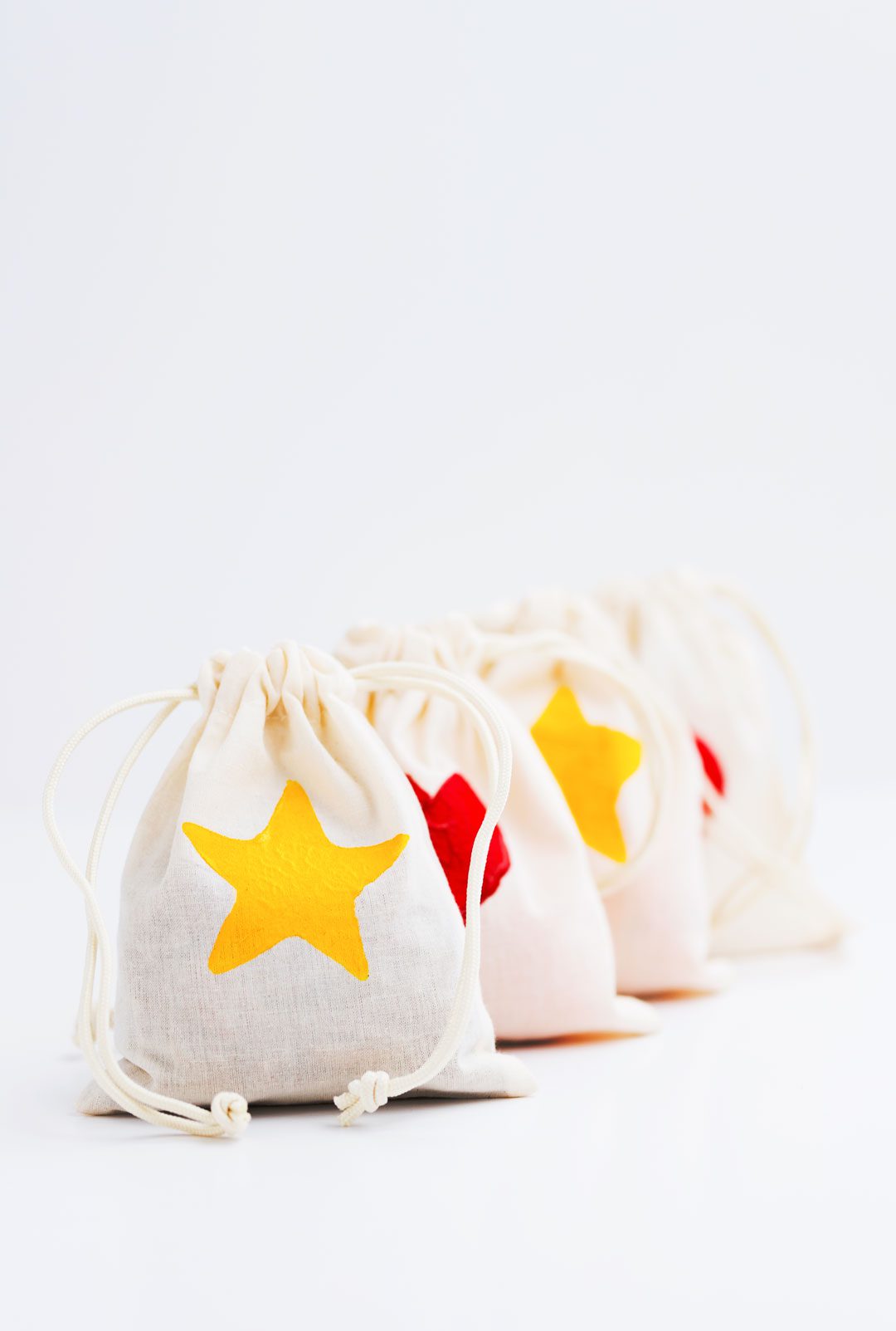 A row of drawstring bags with yellow star and red heart stamp decorations.