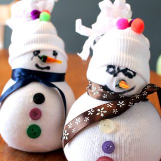 Two sock snowmen with hats, pom poms, ribbons for scarves, buttons, and faces.