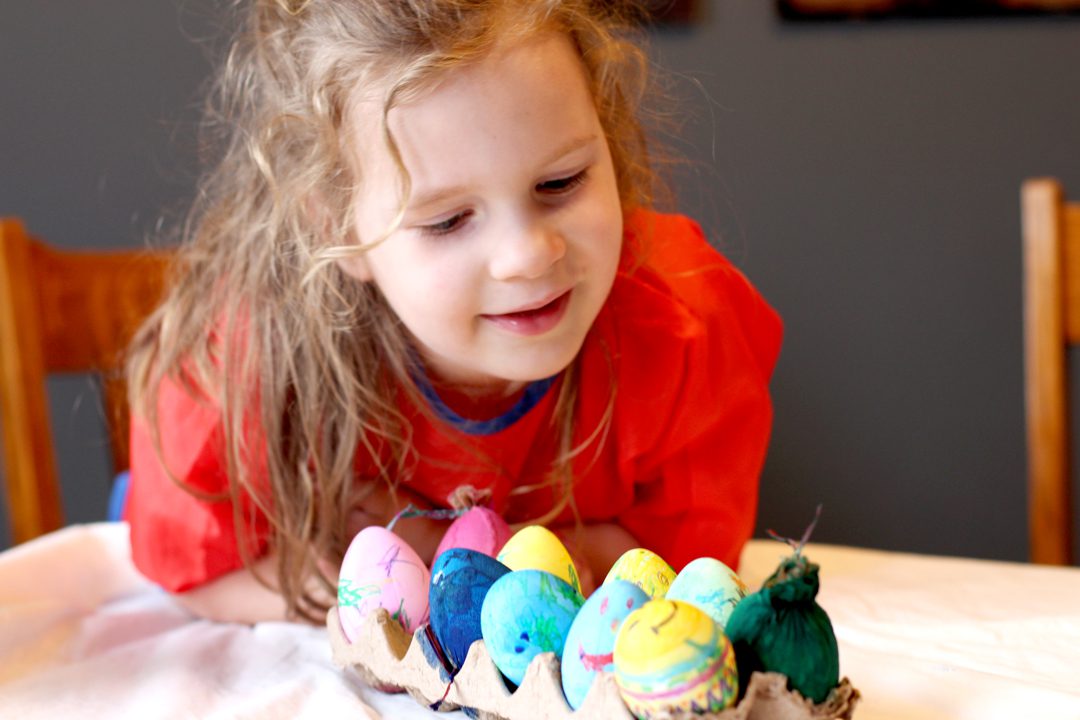 A child looking at colorful decorated Easter Eggs.