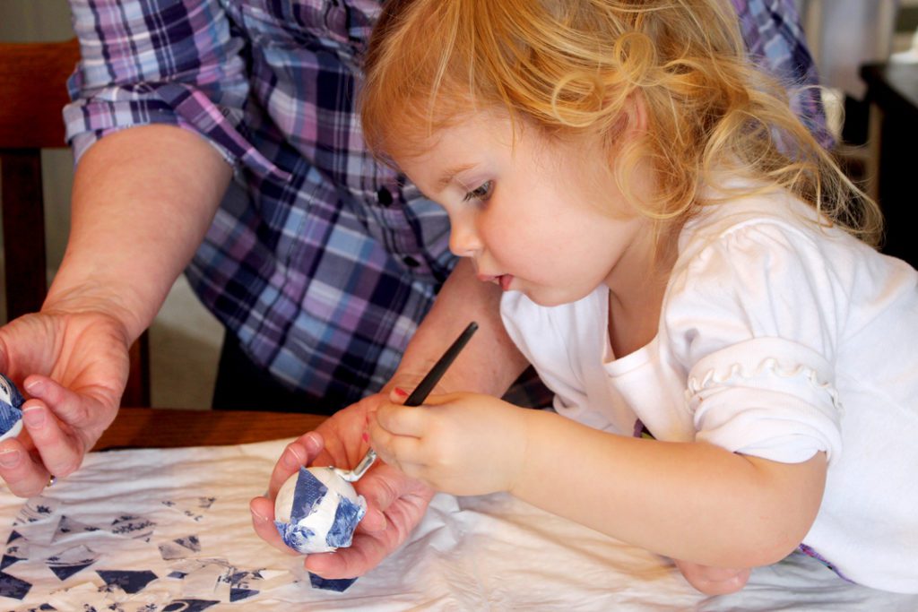 A child painting decoupage on an easter egg.