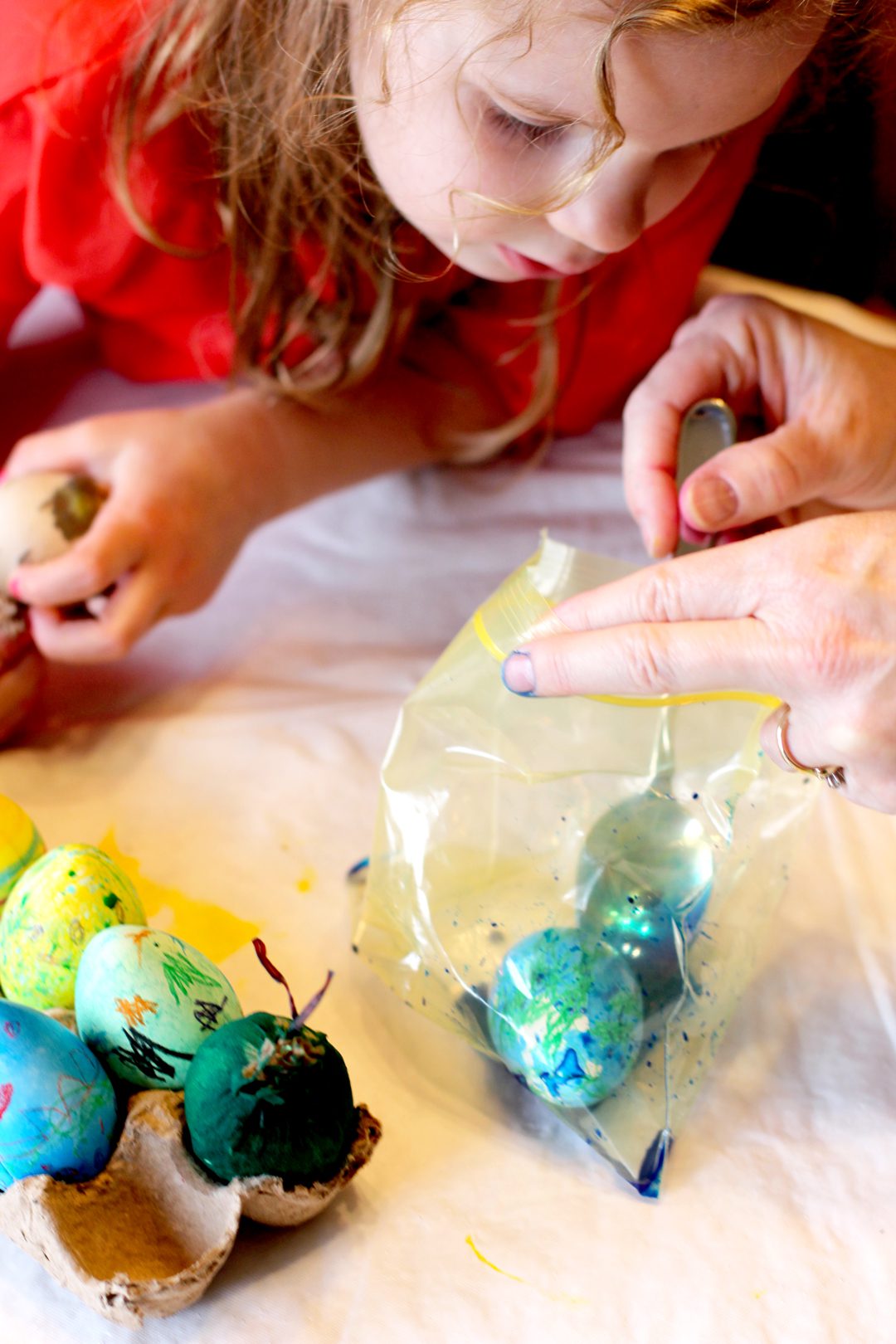 A child watching an easter egg being dyed in a bag.