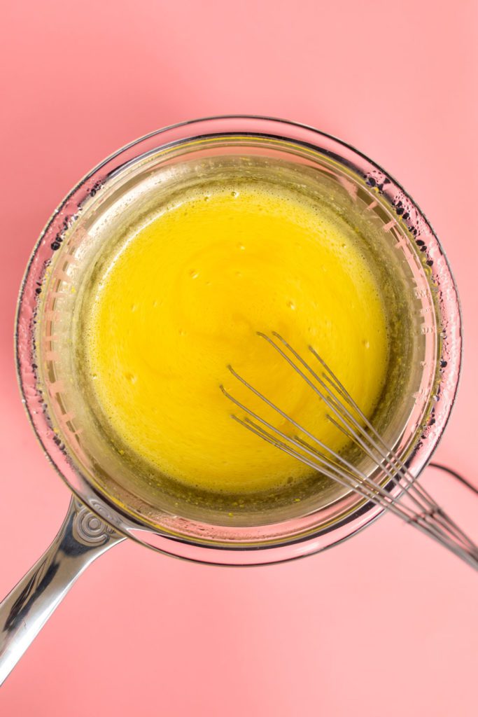 Lemon curd ingredients in a double boiler being whisked.