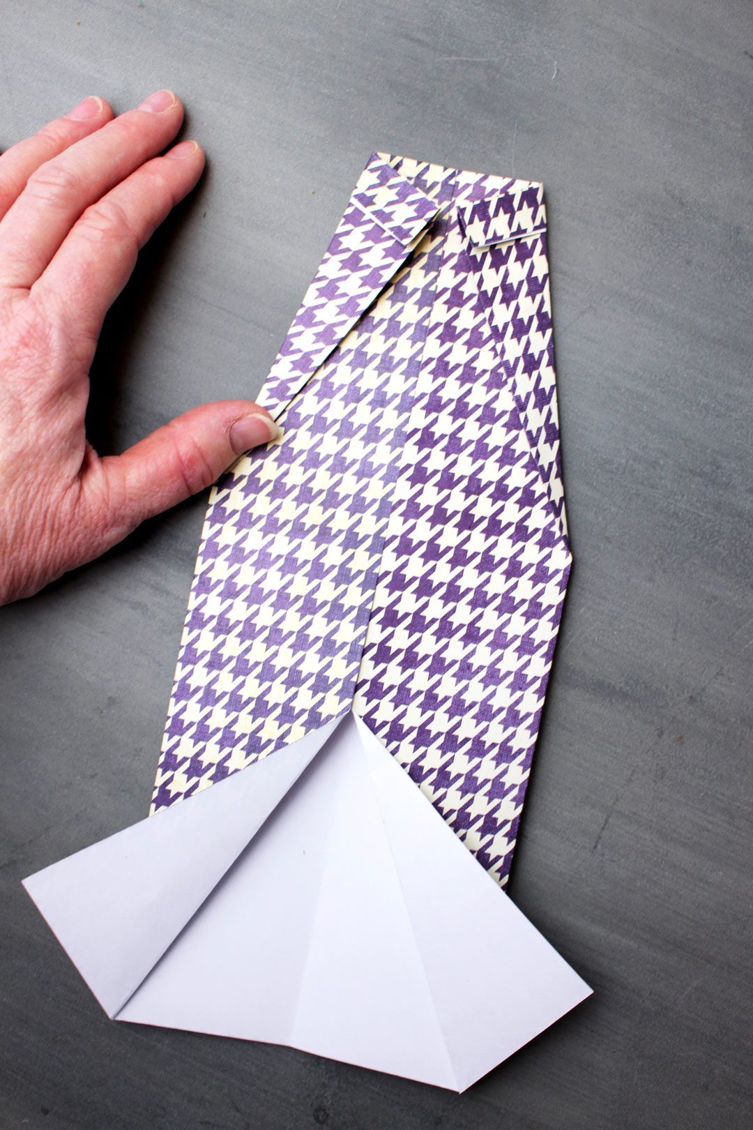 Two corner folds for a purple houndstooth pattern folded origami shirt.