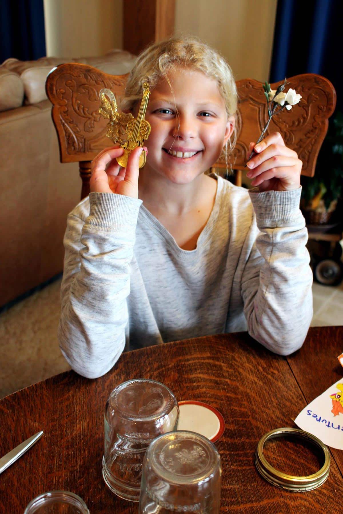 Child holding up flower and ornament to place in their snow globe.