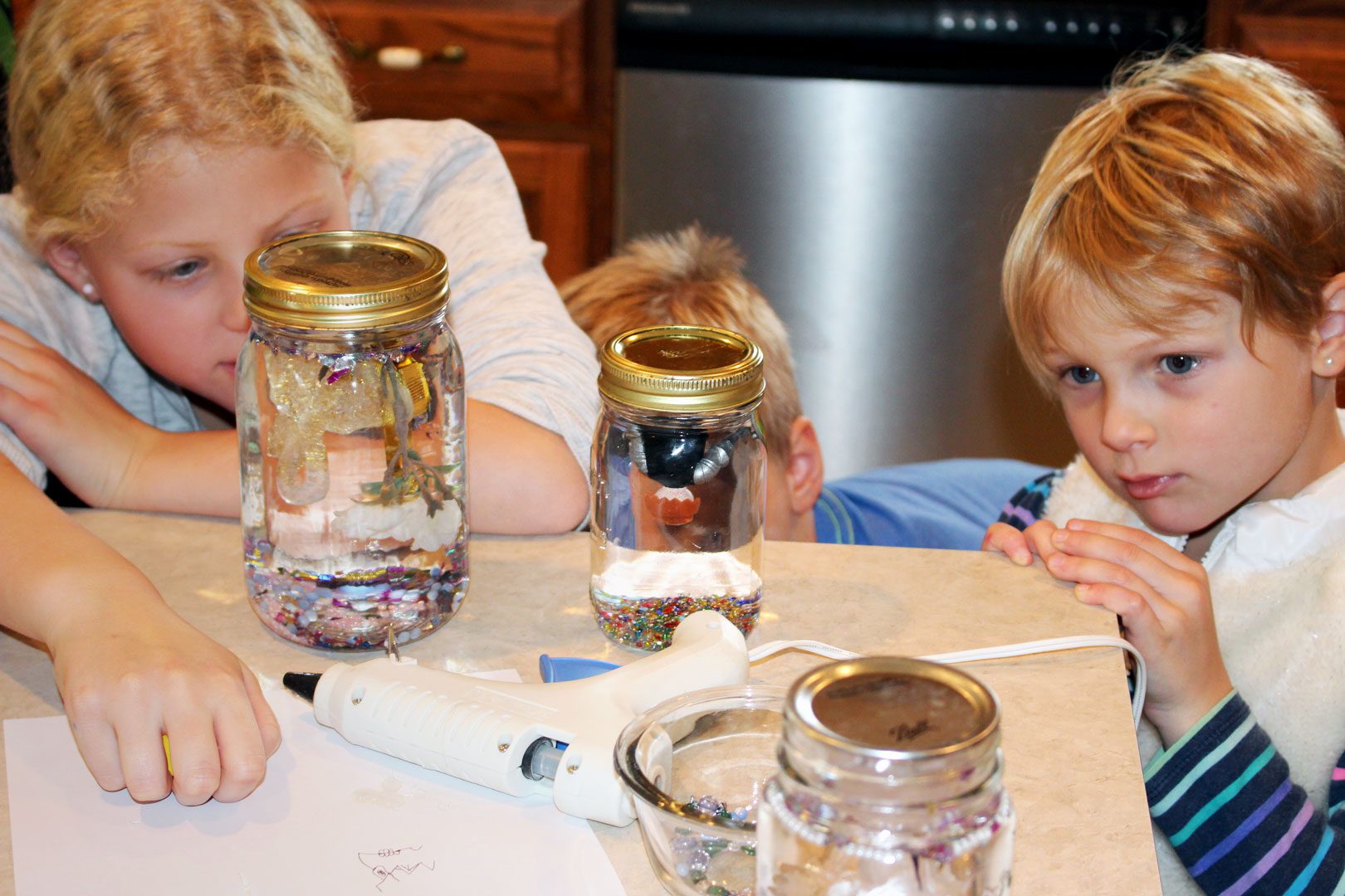 Children waiting for the hot glue to dry on the finished snow globes.