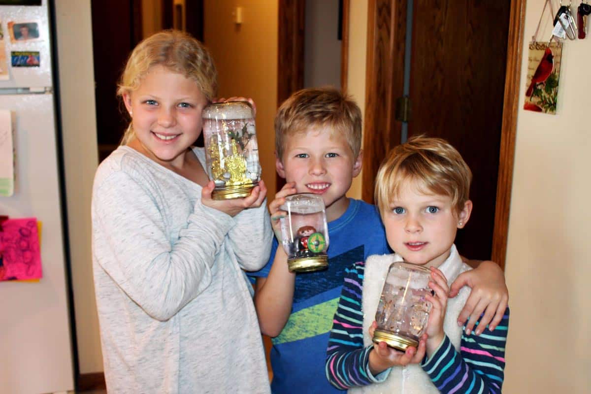 Children holding finished DIY snow globes.