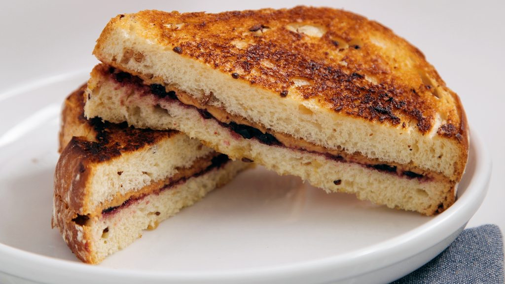A sliced grilled peanut butter and jelly sandwich on a plate.