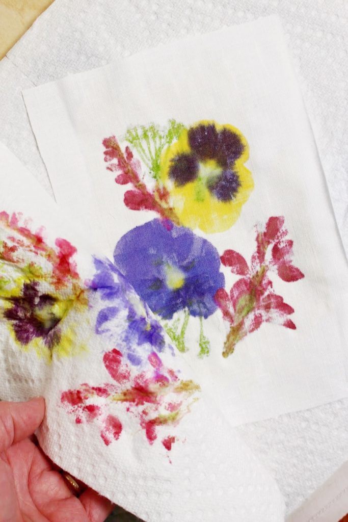 Layers of paper towels being removed from a piece of fabric with colorful flower patterns.