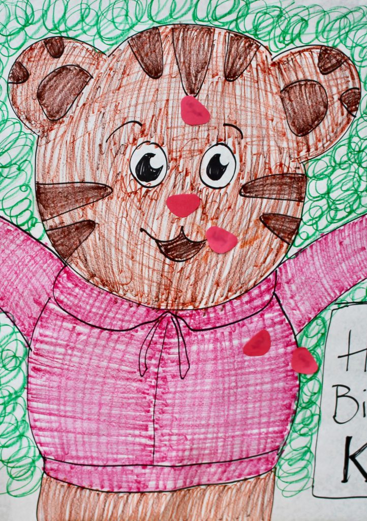 A hand drawn bear on a poster with noses pinned on him after a party.