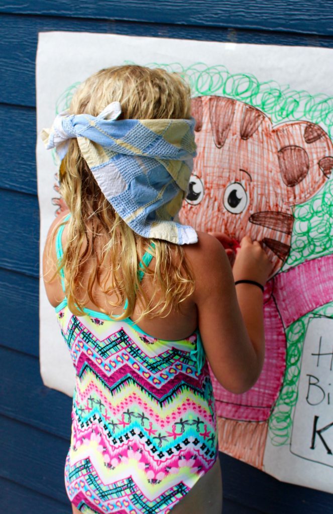 A child blindfolded, pinning the nose on a bear for a game at a party.