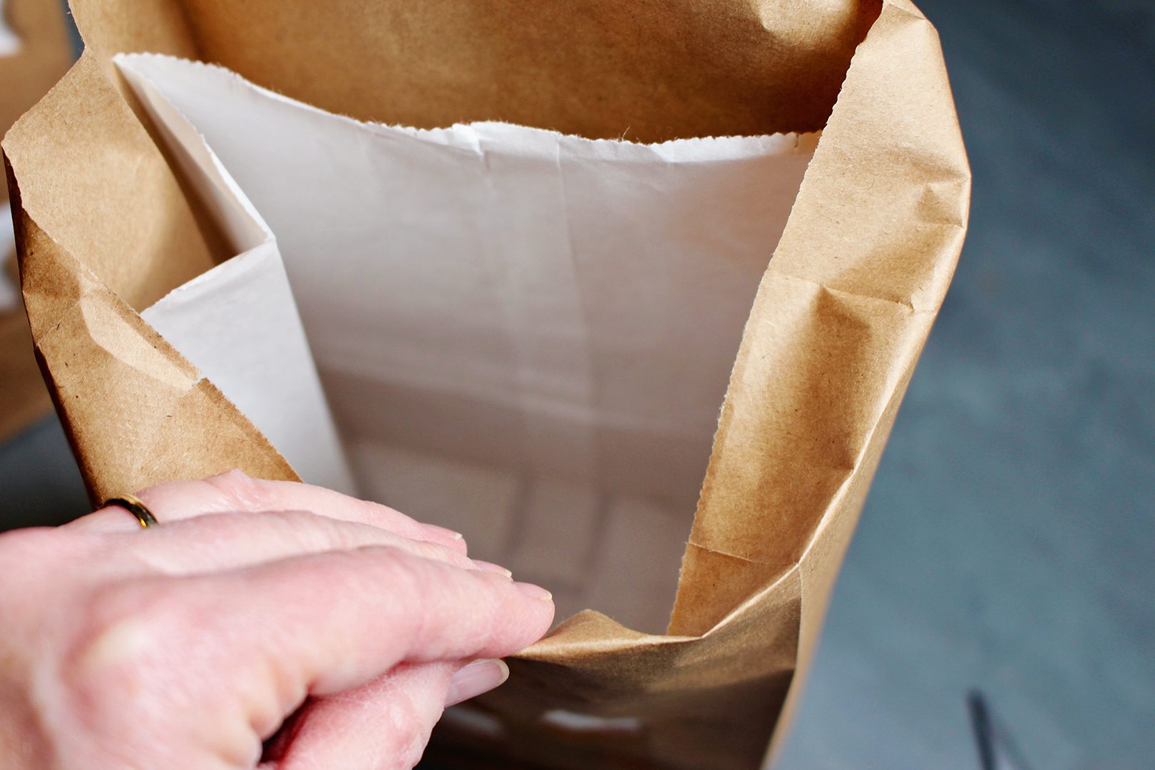 Folding over the edge of a brown paper bag with a white sandwich bag inside.