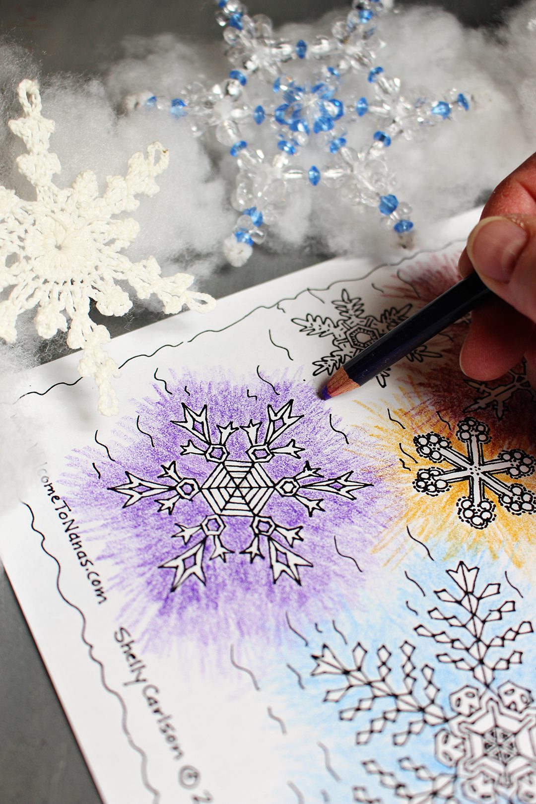 Coloring orange, green, and purple snowflakes with a purple colored pencil.