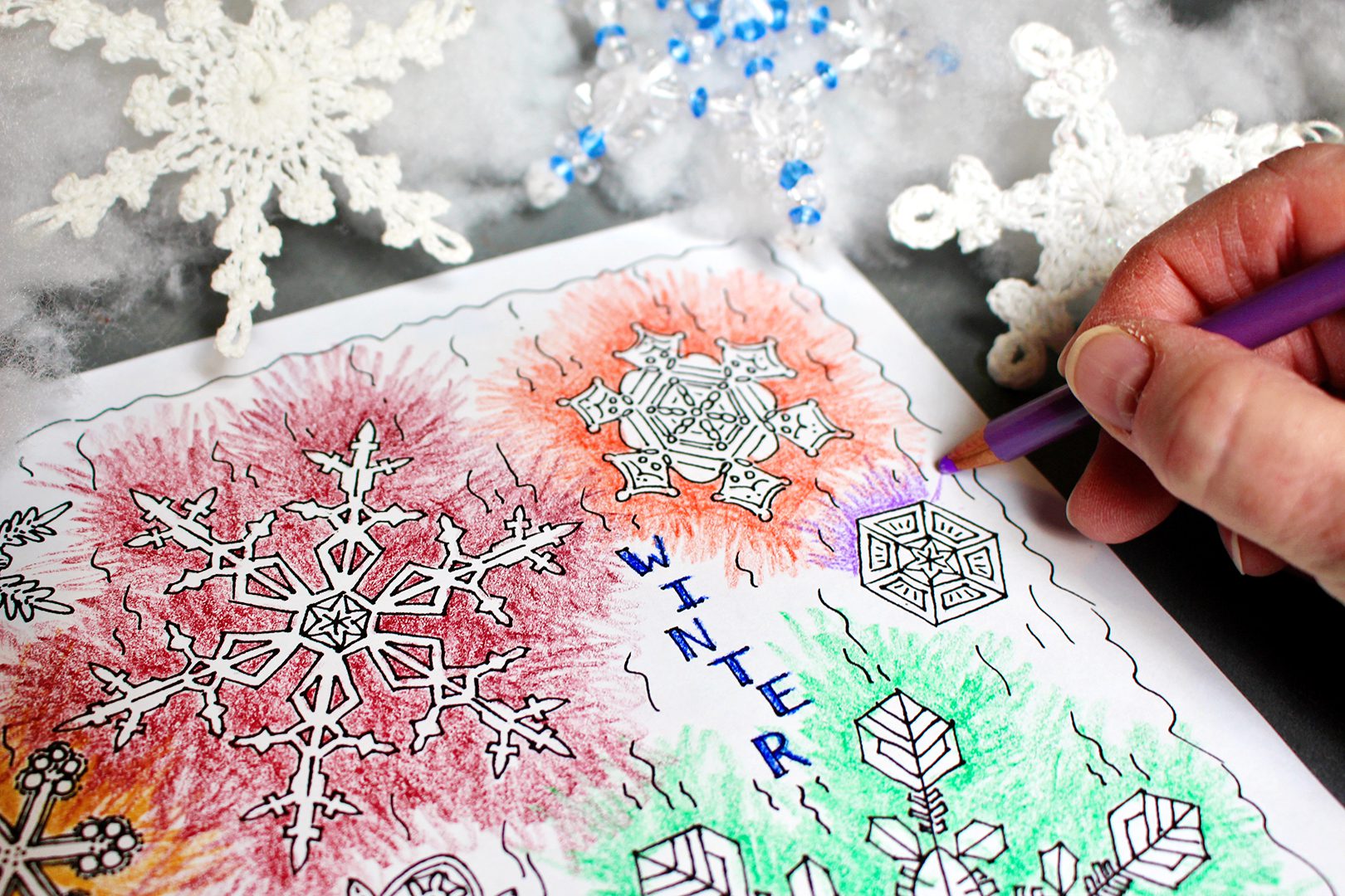 Coloring red, orange, green, and purple snowflakes with a purple colored pencil.