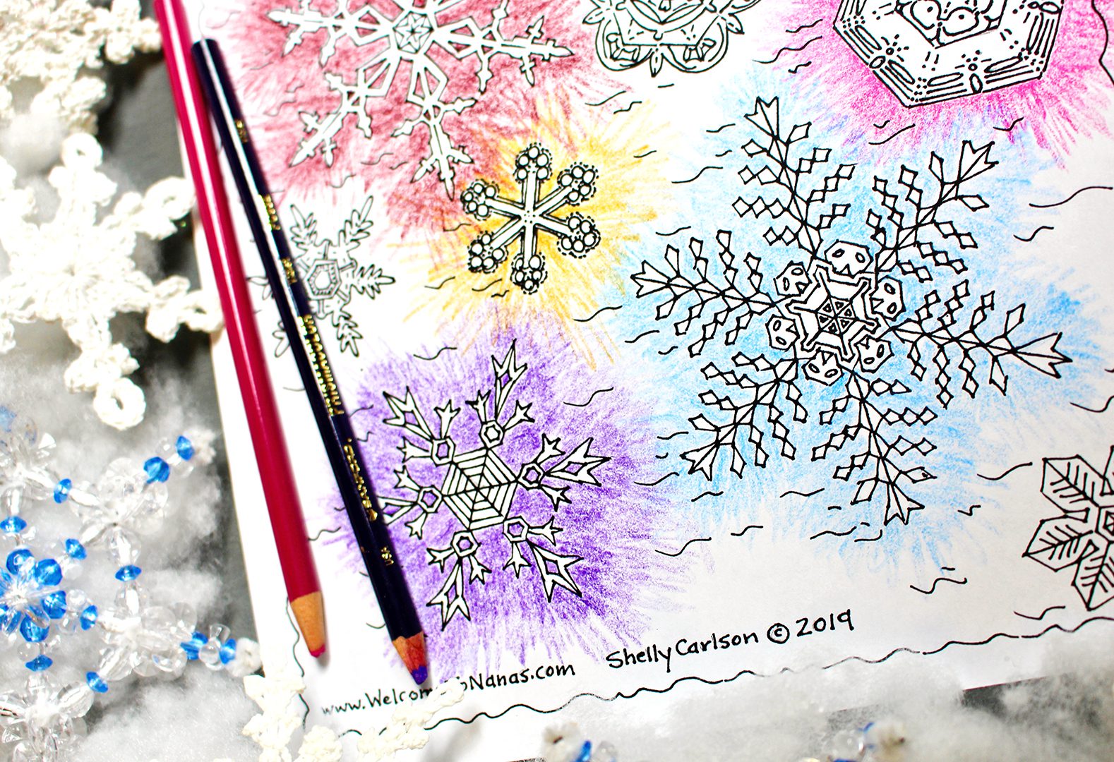 Coloring red, orange, green, and purple snowflakes with a pink and purple colored pencil.