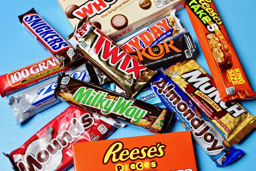 Reese's, Milky Way, Twix, Snickers, Mounds, Almond Joy, and other candy bars in a pile.