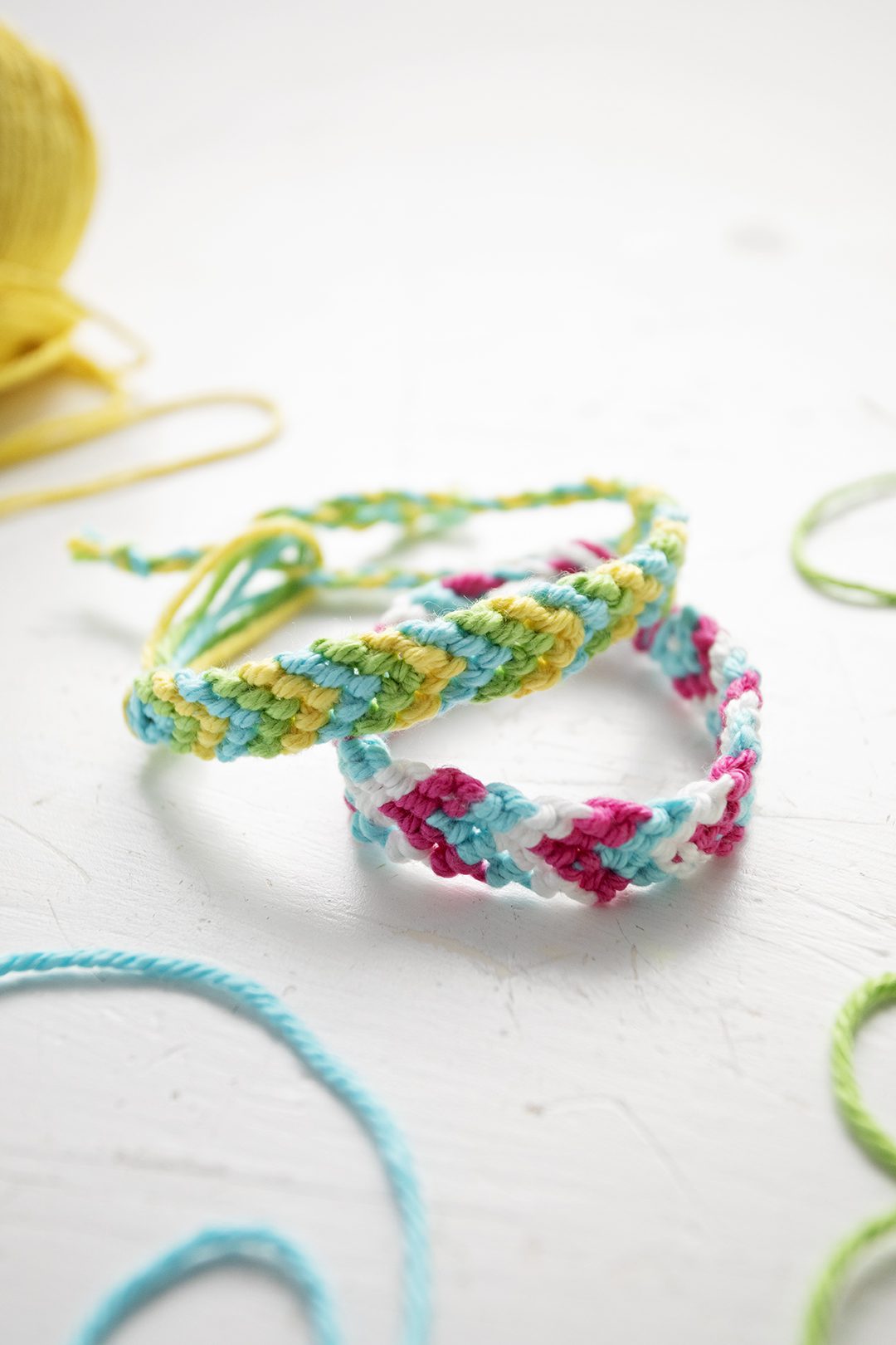 Two chevron pattern bracelets in green, blue, yellow, pink, and white embroidery floss.