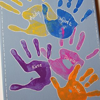 Colorful children's handprints painted on a canvas.