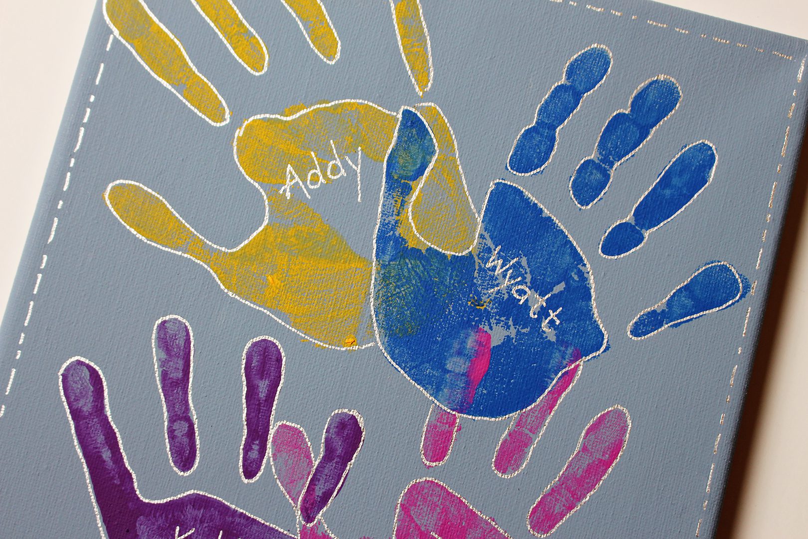 Painted handprints on a canvas with names written on them.