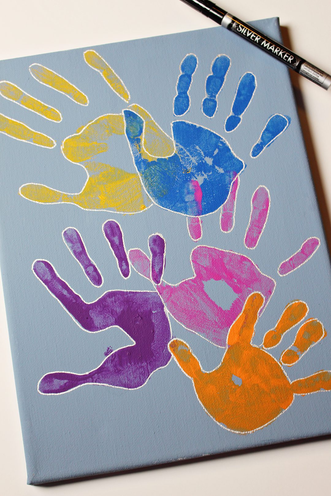 Painted children's handprints on a blue canvas.