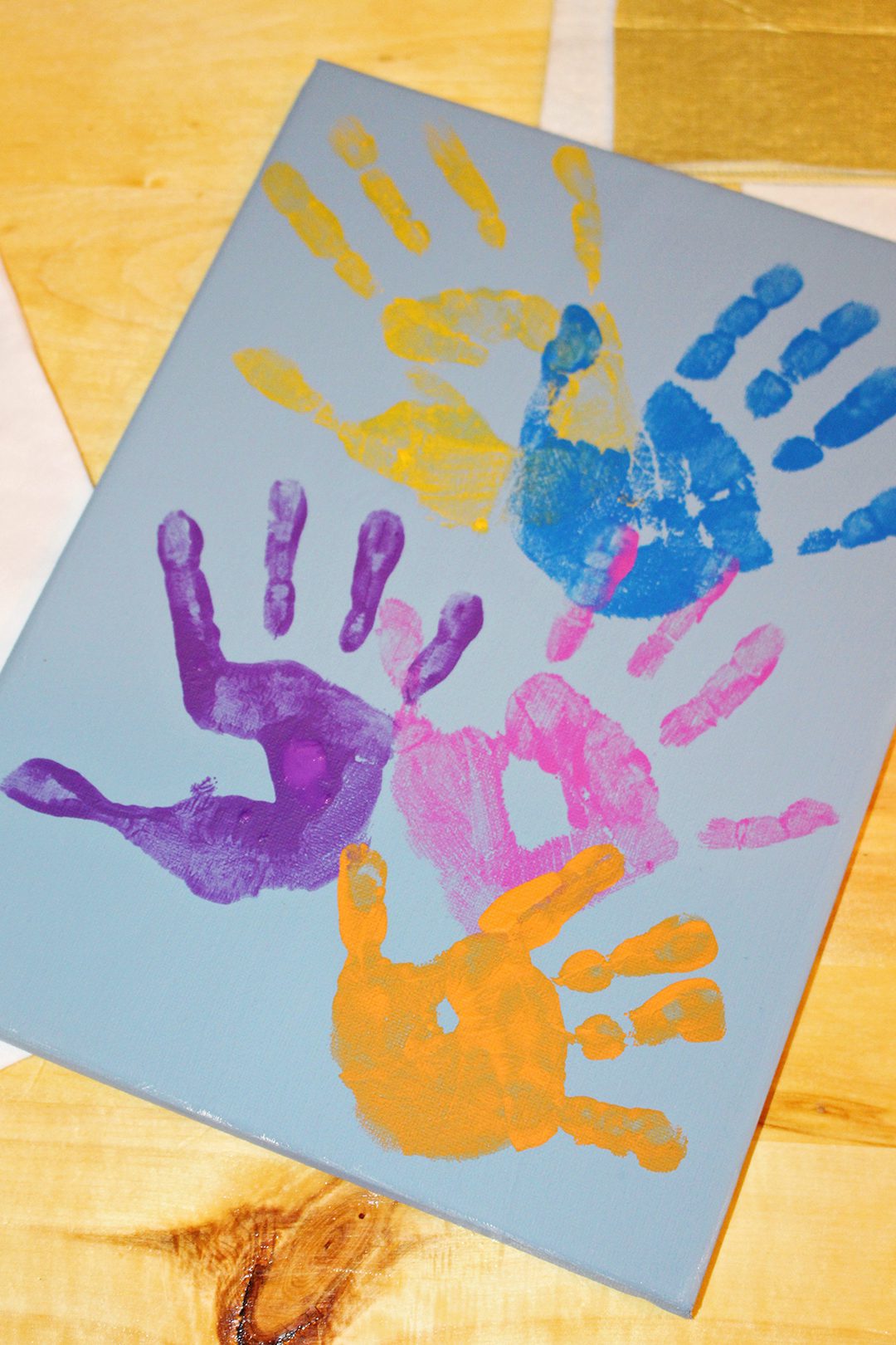 Colorful painted children's handprints on a canvas.