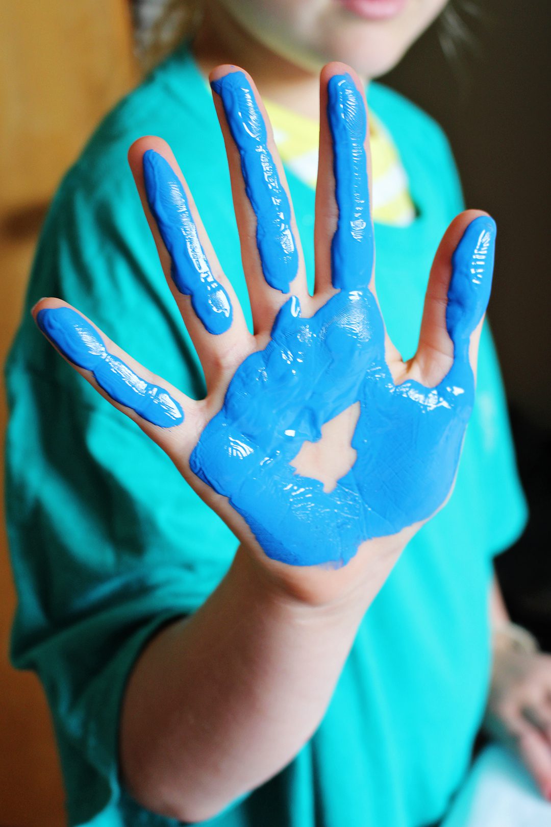 A child with blue paint on their hand.