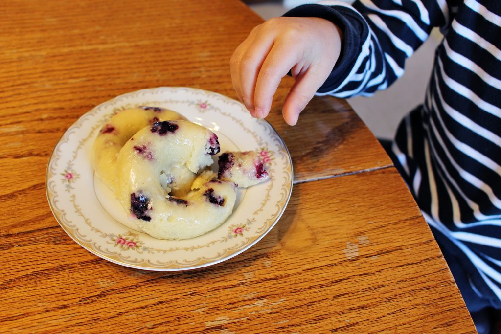 A child eating one of the lemon blueberry donuts.