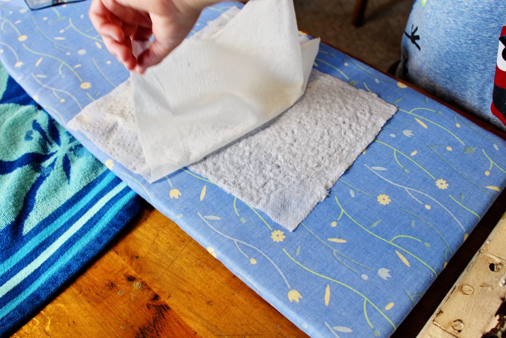 Pulling a paper towel off a page of recycled paper pulp.