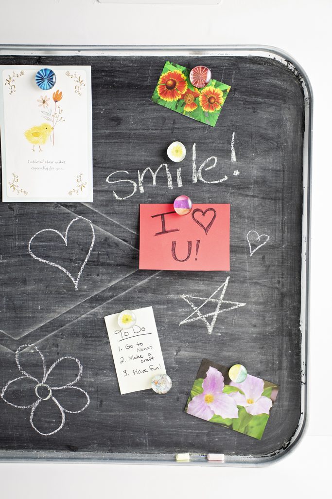 A magnetic tray chalkboard with notes, chalk drawings, and magnets.
