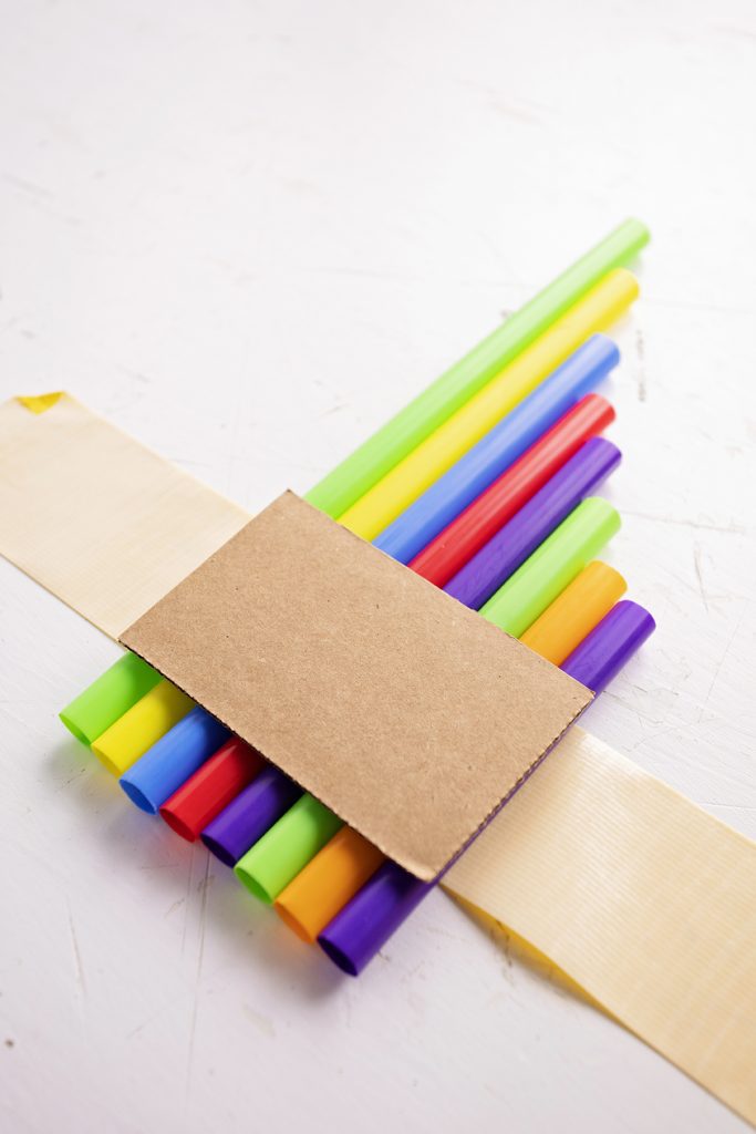 A fife made from large colorful straws, taped together with a piece of cardboard.