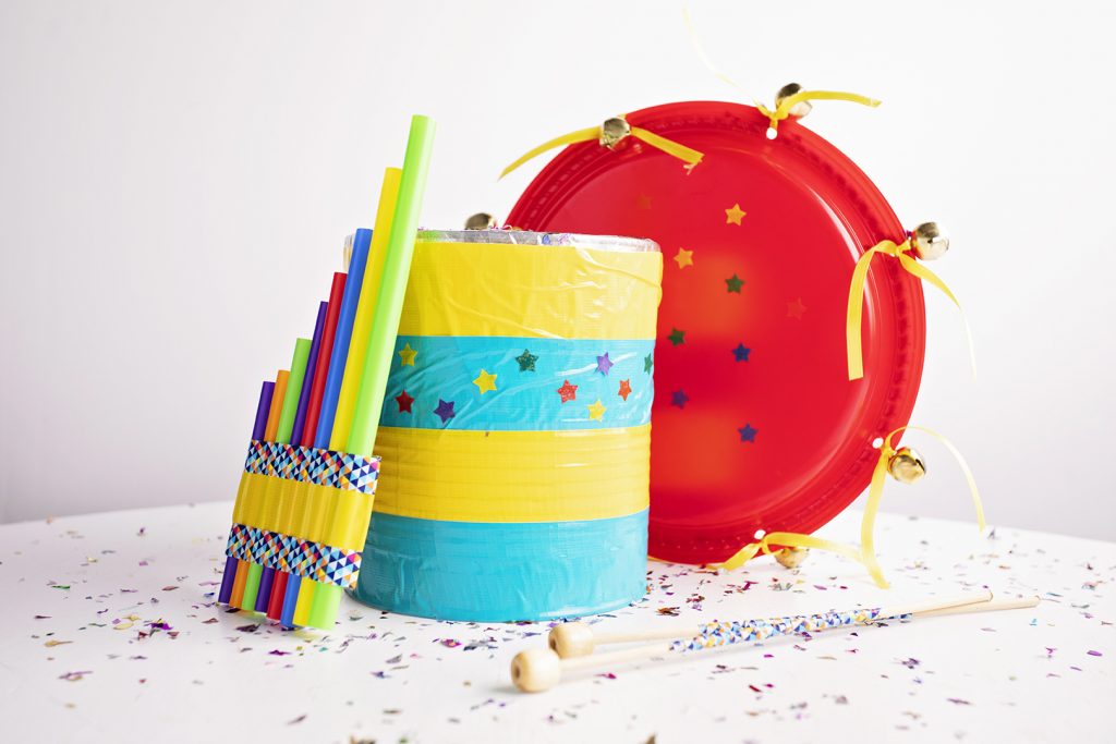 A colorful fife made from straws, a striped drum made from a can, and a red tambourine made from bells and paper plates.
