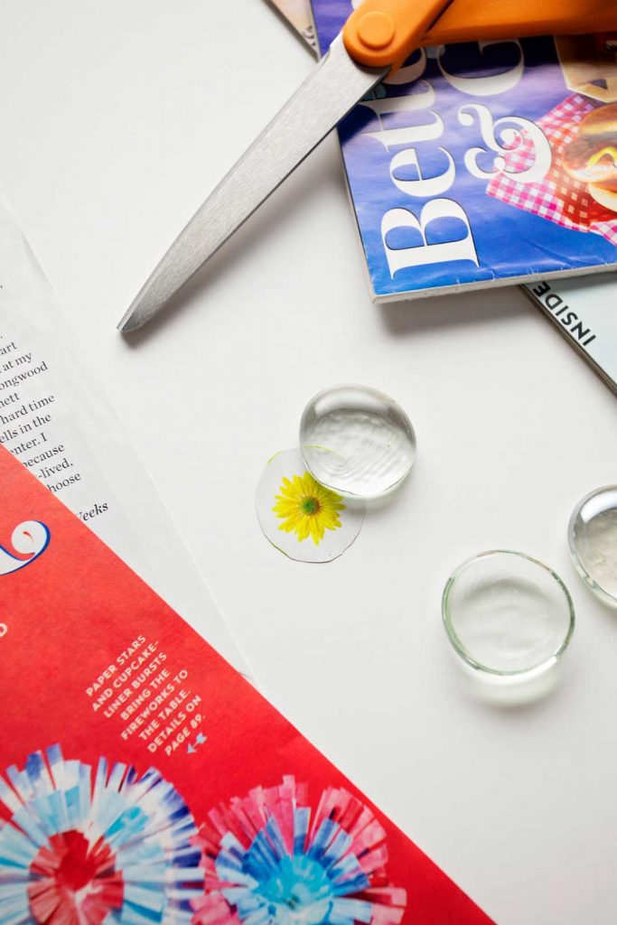 Scissors, magazines, glass gems, and a clipping of a yellow flower.