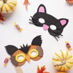Craft foam owl and cat masks surrounded by fall leaves, pumpkins, and candy.
