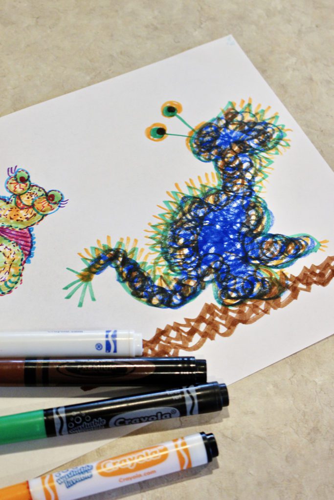A blue scribble monster on a piece of paper with markers. 