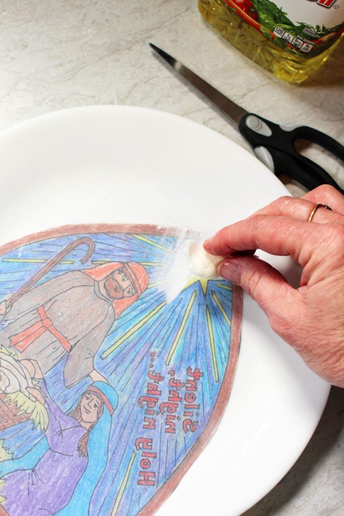 Wiping oil on the back of the coloring page for a stained glass effect.