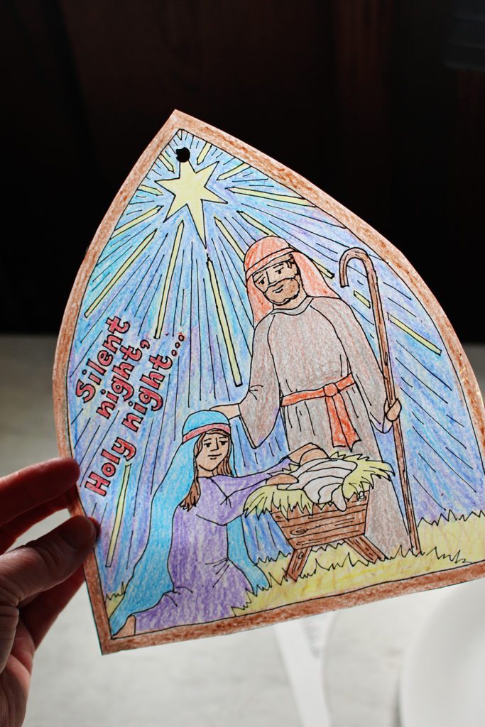 Finished Silent Night Christmas Coloring Page window decoration with light shining through.