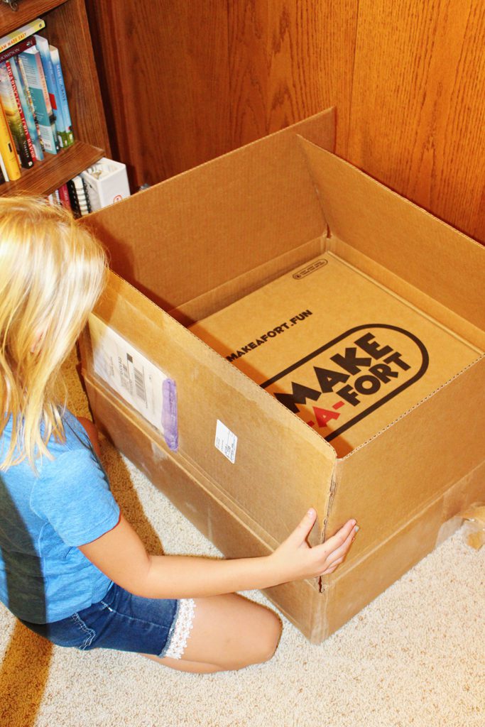 A child opening the Make-A-Fort Kit box