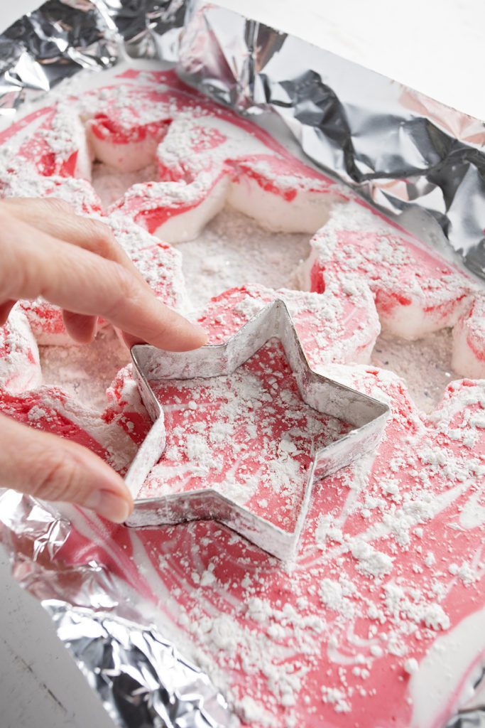Using a star shaped cookie cutter to cut the peppermint marshmallows.