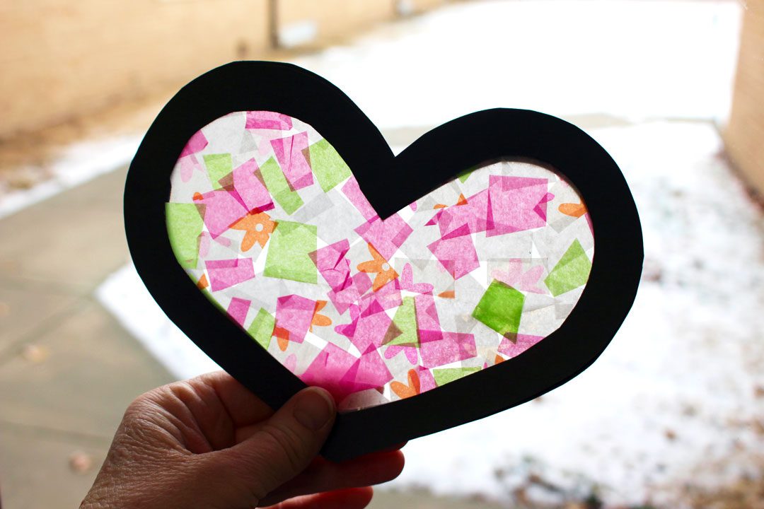 Light shining through a pink and green stained glass Valentine's Day heart card.