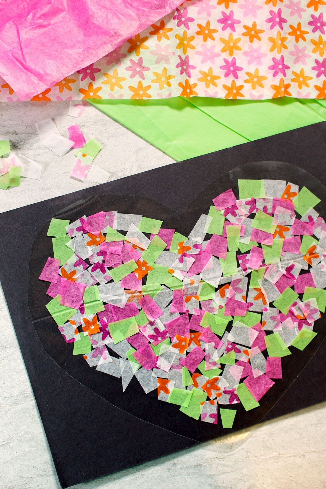 Pink, green, and white tissue paper attached to contact paper in a heart shape.