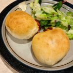 Homemade pizza pockets on a dinner plate with a salad.