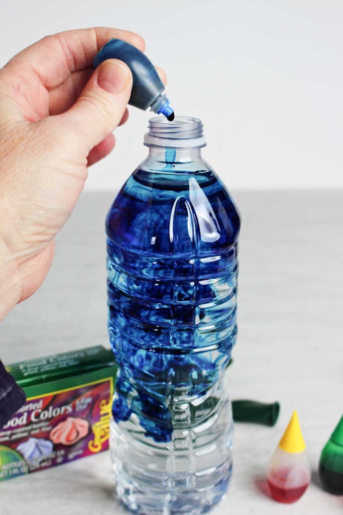 Dropping blue food coloring into a bottle of water.