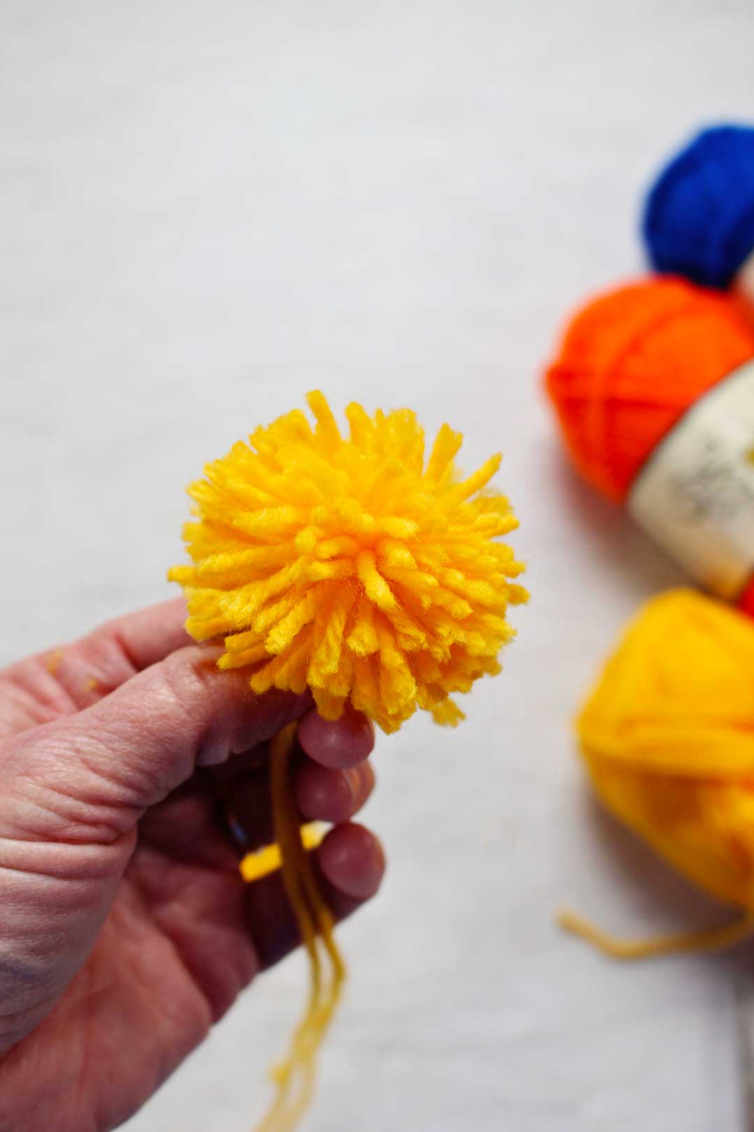 A yellow pom pom made from yarn.