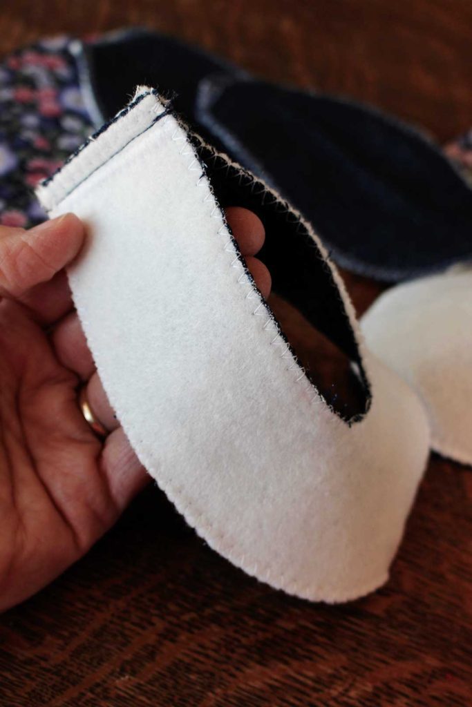 White and denim fabric sewed together to make the sides of a pair of baby shoes.