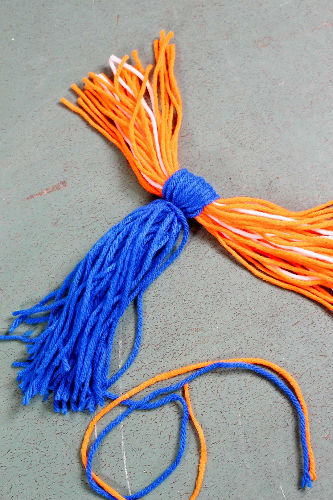 A bunch of blue yarn folded around strands of orange and white yarn.