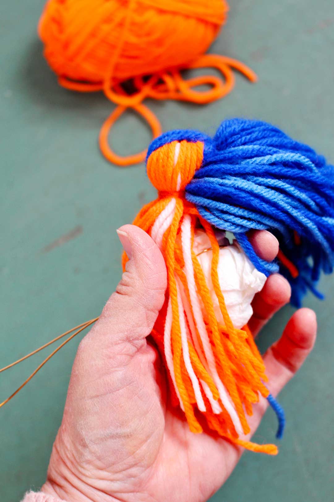 wrapping orange yarn around a ball of paper towels.