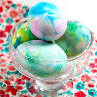 Pink, blue, green, and yellow tie-dyed Easter eggs displayed in a dish.
