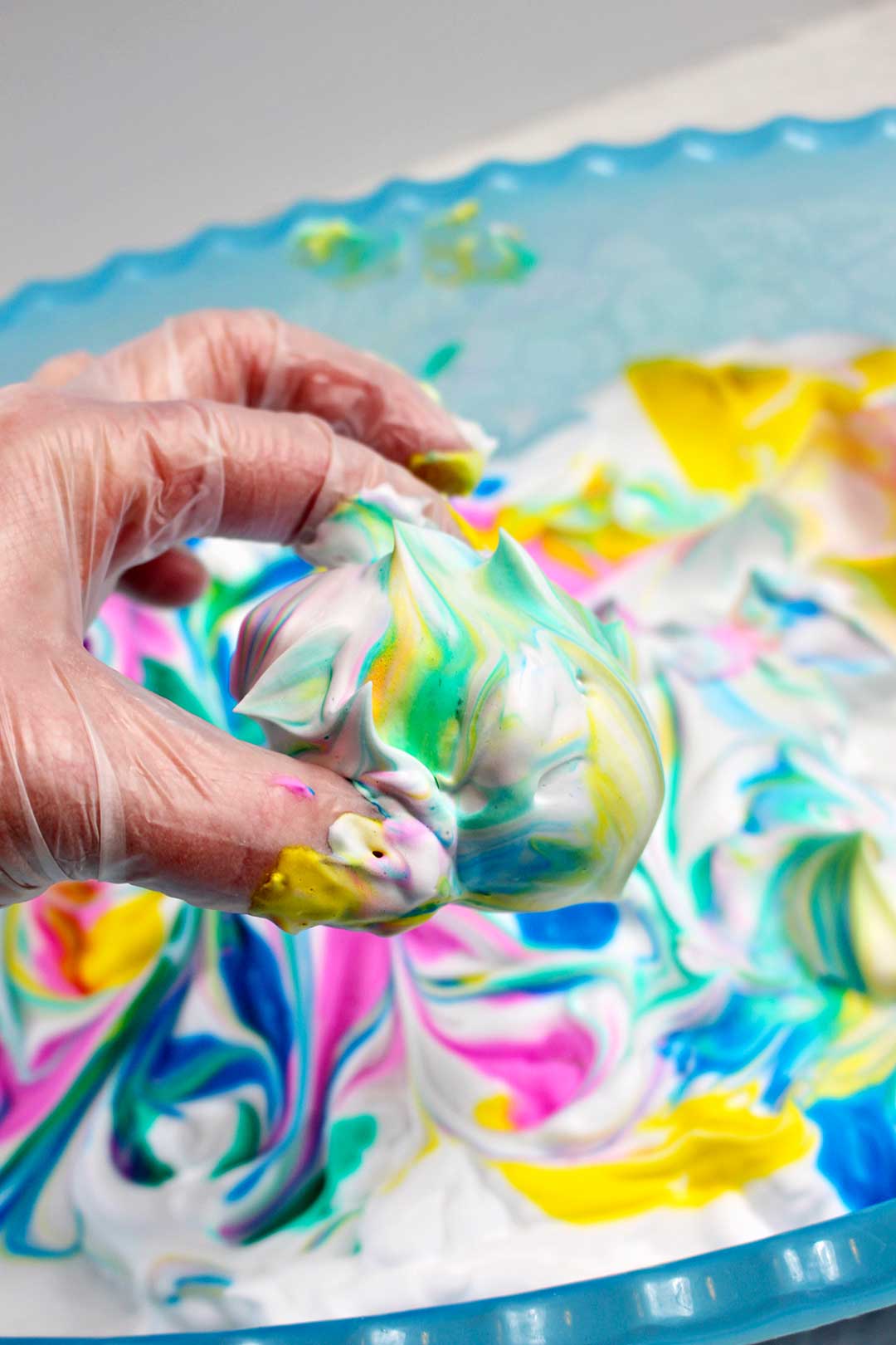 An egg covered in yellow, green, blue, and pink swirled shaving cream.