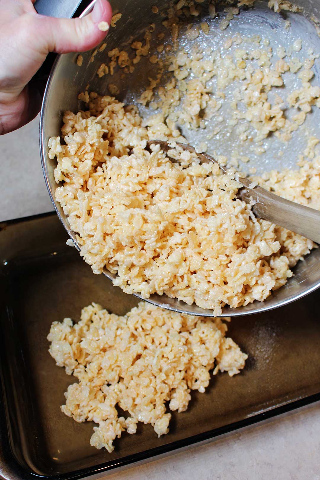 Rice crispy treat mixture being poured into a 9x13 pan.